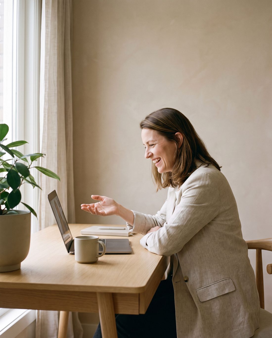 A bookkeeper laughing during a video call at her desk.